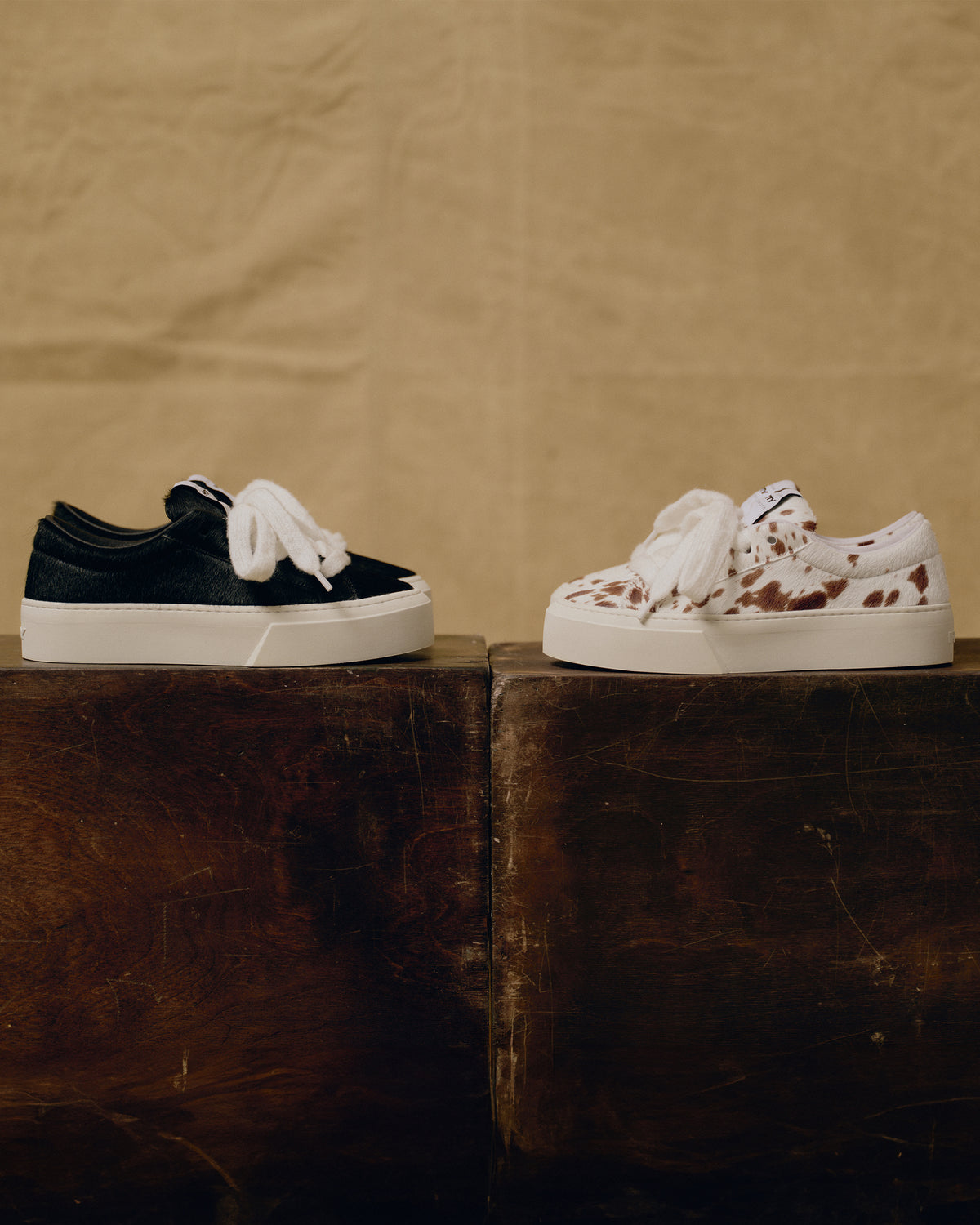 The Black Pony and Bambi OG sneakers side by side on a wooden block